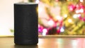 Amazon Alexa personal assistant connected loudspeaker on a wooden table in a Smart Home livingroom next to a Christmas tree. Royalty Free Stock Photo