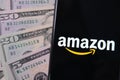 Amazon logo on smartphone placed next to dollar banknotes