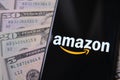 Amazon logo on smartphone placed next to dollar banknotes