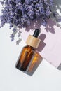 Amber dropper bottle with serum, tonic or essential oil with lavender flowers on pink concrete podium. Royalty Free Stock Photo