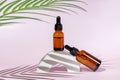 Amber dropper bottlesa on light pink background. Care about face, hands and body skin. Women beauty product. Empty place for logo