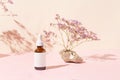 Amber glass bottle of essential oil or serum with pipette on pink pastel background with shadows. Natural skincare cosmetic