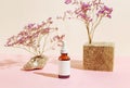 Amber glass bottle of essential oil or serum with pipette and wooden podium on pink pastel background with shadows. Natural