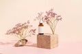 Amber glass bottle of essential oil or serum with pipette on wooden podium on pink pastel background with shadows. Natural