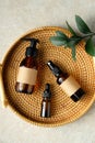 Amber glass bottle of organic cosmetics and green plant leaf in rattan plate in bathroom. SPA natural beauty products set. Flat Royalty Free Stock Photo