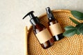 Amber glass bottles of natural cosmetics and green leaf in rattan plate. SPA organic bathroom beauty products. Flat lay, top view