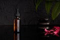 Amber glass bottles for oil or serum on black glass, black texture background, copy space, cosmetics background mock-up