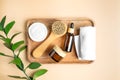 Amber glass cosmetics bottles on wooden tray with ruskus leaves and white towels. Set of natural organic SPA beauty