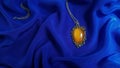 Amber jewelry is placed on a blue navy silk fabric. Luxury pendant with Baltic amber.