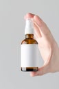 Amber Spray Bottle Mock-Up. Blank Label - Male hands holding an amber spray bottle on a gray background