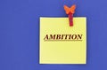 AMBITION - word on a yellow piece of paper on a blue background