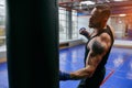 Ambitious boxer man hiting heavy bag at gym