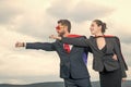 ambitious business couple in superhero suit on sky background