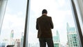 Ambitious businessman standing in ornamented office on cityscappe background