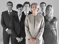 Ambitious businesswoman with team of professionals against gray background