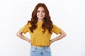 Ambitious and confident cute hipster girl with red curly hair in yellow t-shirt hold hands on waist motivated and self