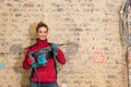 Ambitious craftswoman with caulking hammer in front of brick wall in bare brickwork Royalty Free Stock Photo