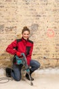 Ambitious craftswoman with caulking hammer in front of brick wall in bare brickwork Royalty Free Stock Photo