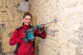 Ambitious craftswoman with caulking hammer in front of brick wall in bare brickwork Royalty Free Stock Photo