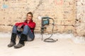 Ambitious craftswoman sitting on floor in front of brick wall in Royalty Free Stock Photo