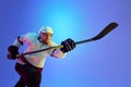 Ambitious man, hockey player posing with stick, showing his determination against gradient blue background in neon light