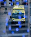 An ambulance driving down a road with Christmas light around in the foreground.