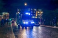 An ambulance on the road, with blue emergency lights flashing, in the city at night
