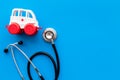 Ambulance service concept. Ambulance vehicle toy near stethoscope on blue background top view copy space