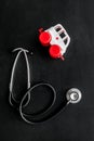 Ambulance service concept. Ambulance vehicle toy near stethoscope on black background top view