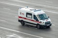 Ambulance van Ford Transit driving fast to an urgent call along city street. Children\'s ambulance car in motion