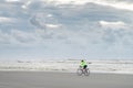 Young woman cycles on the beach during the sunset