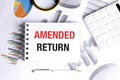Amended return text on notepad with calculator, graphs and pen representing tax correction or financial adjustment Royalty Free Stock Photo