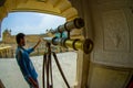 Amer, India - September 19, 2017: Unidentified man manipulating a golden telescope inside of the palace in Amer, in