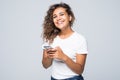 America latin mixed race woman with curly hair holding mobile phone and smiling on camera isolated over white background Royalty Free Stock Photo