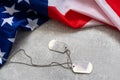 America United States flag and chain dog tags, military symbolizing, studio shot on concrete board background, US Royalty Free Stock Photo