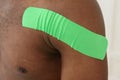 American african man with green kinesiotaping on sholder on white background, copy space, closeup.