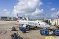 American airlines aircraft on the tarmac during baggage loading against a blue sky with white clouds. Royalty Free Stock Photo