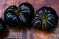 Black heirloom tomatoes on reddish wooden cutting board Royalty Free Stock Photo