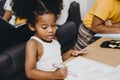 American Black preschool daughter kids doing homework learning education with her sister living together at home