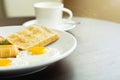 American breakfast and hot coffee in a white ceramic coffee cup on a wooden table with warm morning sunshine and lens flare