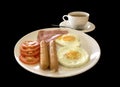 American breakfast with sausage, tomato, ham, fried eggs, bacon, and coffee, black background Royalty Free Stock Photo