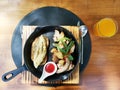 American Breakfast set, Omelette, sausage, bacon, fresh tomato and vegetable in black plate with spoon fork and knife on a wooden Royalty Free Stock Photo