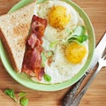 American breakfast with sunny side up eggs, bacon, toast, coffee, green salad, wood background. Top view Royalty Free Stock Photo