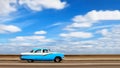 American bright blue retro car on the seafront of the capital of Cuba Havana against the blue sky with white clouds. Motion blur.