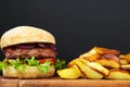 American burger with fried potatoes on wooden board. Royalty Free Stock Photo