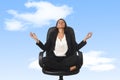 American business woman sitting at office chair in lotus posture practicing yoga and meditation