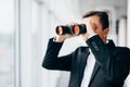 American businessman using binoculars look in windows in office Royalty Free Stock Photo