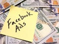 American cash money and yellow paper note with text Facebook Ads