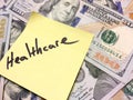 American cash money and yellow paper note with text Healthcare