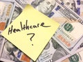 American cash money and yellow paper note with text Healthcare question mark